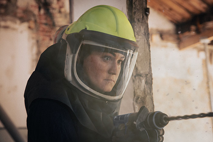 Worker wearing a head-mounted PAPR in a construction setting.